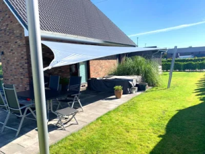 Modernes Sonnensegel über Terrasse im grünen Garten